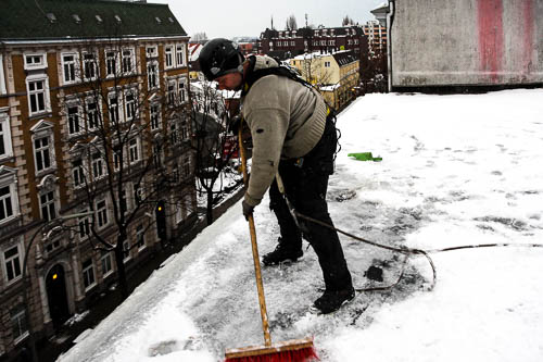 Höhenarbeiter entfernt Schnee vom Dach