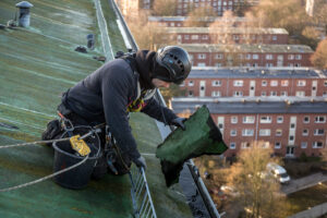 Höhenarbeiter sammelt Dachpappe aus der Regenrinne